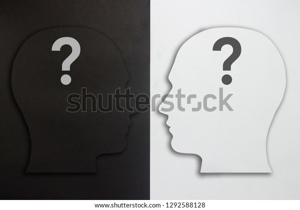 Two paper\
heads with a question mark, black and white on a black and white\
background. The concept of a split personality, different opinions,\
dispute, war. Flat lay, top\
view.