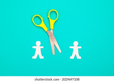 Two Paper Human Dolls With Scissors On Green Background, Break Up Relations, Disconnect, Or Social Distancing Concept