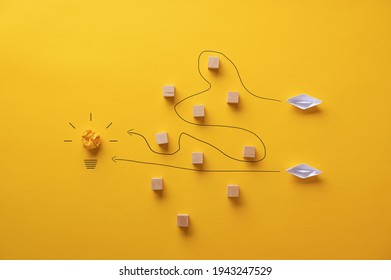 Two paper origami made boats trying to reach their goals and ambitions by travelling different paths. - Shutterstock ID 1943247529