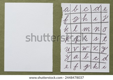 two paper sheets, one blank, the other with cursive alphabet, on rough green scrapbooking paper