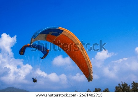 Two para gliders glide gracefully through clear skies amidst picturesque clouds and rolling hilltops, Embracing freedom and the beauty of nature.