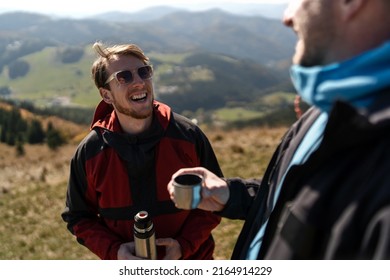 Two Paragliders Men Standing On The Top Of Mountain And Drinking Tea.