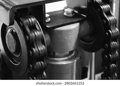 Two parallel metal chains hang vertically inside machine. Cylindrical shaft divides frame. Exposed wiring mechanical parts fill background tech industrial technology background