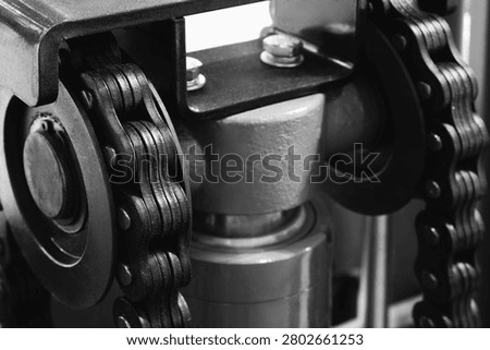 Two parallel metal chains hang vertically inside machine. Cylindrical shaft divides frame. Exposed wiring mechanical parts fill background tech industrial technology background