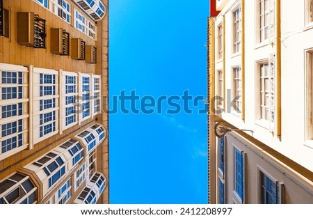 Two parallel residential apartment buildings against a blue sky background, view from below.