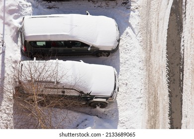 Two Parked Cars Covered In Snow
