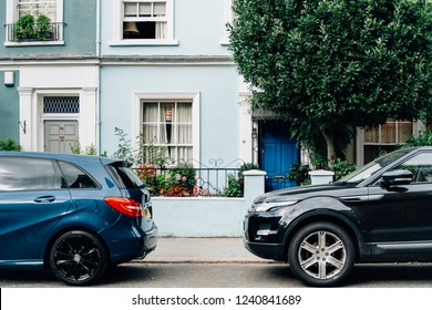 Two Parked Cars In Front Of An Apartment Entrance