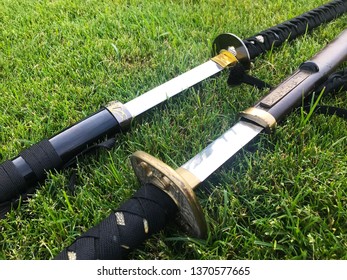 Two partially unsheathed katanas on some vibrant, green grass. These swords have a very rich history in Japan; and represent much more than just weaponry. 