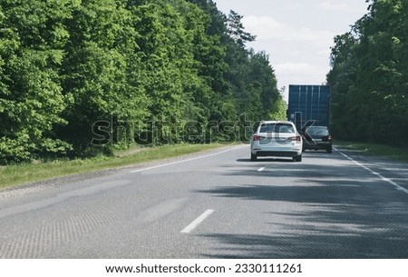 Two passenger cars make a double overtaking of a truck on a narrow road