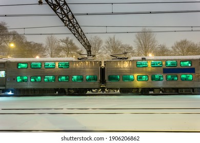 Two Passenger Train Cars At Rest In The Snow In The Evening On Overcast Night In Urban Chicago