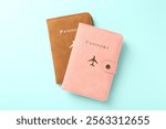 Two passports in bright covers on turquoise background, top view
