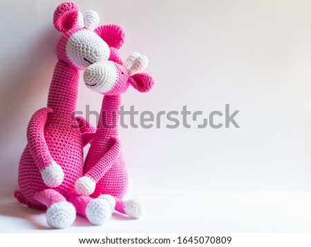 Two pastel pink crochet giraffe dolls embraced
