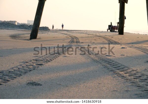 Two
paths meeting on beach tire tracks in sand at
sunrise