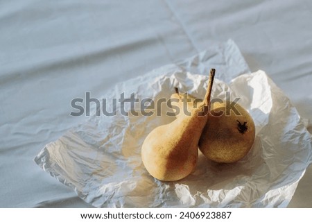 Two pear fruits on the bedsheet in sunlight. Summer or autumn still life. Top view.