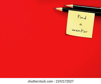 Two Pencil On Red Copy Space Background With Handwritten Note FIND A MENTOR, Professional Who Informally Guides Less Experienced Person (mentee), To Help With Job Requirement Or Long-term Career Goal 