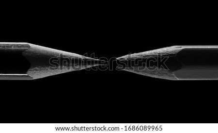 two pencils are isolated on a black background, one pencil is sharp, the other is blunt