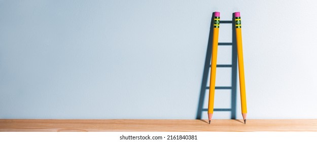 Two Pencils On Desk Casting Shadow Of Ladder - Success Through Education Concept