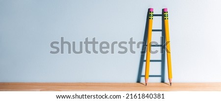 Two Pencils On Desk Casting Shadow Of Ladder - Success Through Education Concept