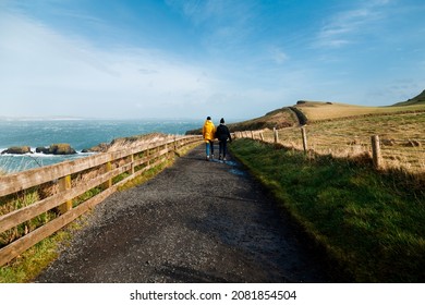 Two People Along A Beautiful Path In Giant's Causeway, Northern Ireland. An Ideal Destination For A Hiking Tour And Exploring A Geological Wonder. UNESCO World Heritage.