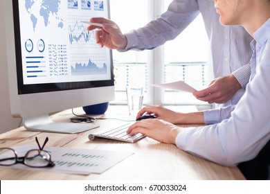 Two people analyzing stock market investment strategy with key performance indicator on financial dashboard and business intelligence on computer - Powered by Shutterstock