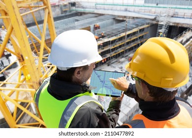 two people architect engineer worker on major constructionsite checking progress report on computer laptop tablet together as team 