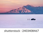 Two people with car on Bonneville Salt Flats near Salt Lake City at sunset. Utah. USA