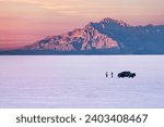 Two people with car on Salt Flats near Salt Lake City at sunset. Utah. USA