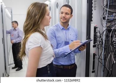 Two People Checking Servers With One Holding Clipboard In Data Center