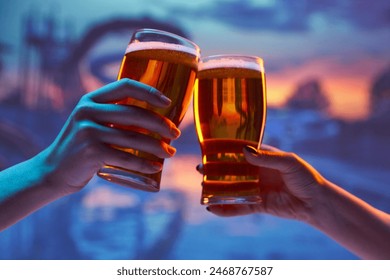 Two people clinking beer glasses against vibrant sunset background, with silhouettes of water slides in the background. Concept of leisure time, refreshment, party, celebration - Powered by Shutterstock