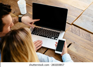 Zwei Personen vergleichen Laptop und Smartphone-Display - Mock up