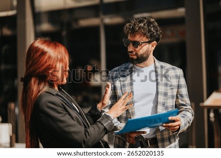 Two people converse over a document, engaging in a professional discussion outdoors.