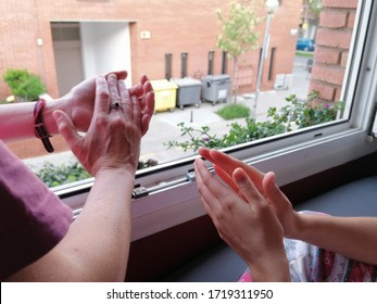 Two People Of Different Ages Clapping Hands From The Window