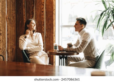 Two People Engaged in Casual Conversation at a Cozy Cafe During the Day - Powered by Shutterstock