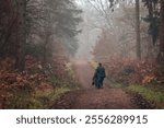 Two people enjoying a peaceful winter walk in the misty Bramfield Woods in Hertfordshire, UK