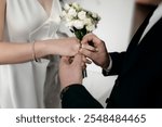 Two people exchange rings in a wedding ceremony, one placing a ring on the other