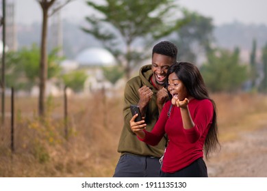 Two People Feeling Excited And Happy As They Look At A Phone Together They Rejoice