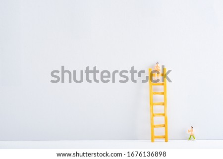 Two people figures with ladder on white surface on grey background, concept of equality rights