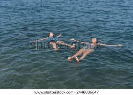 Two people float on their backs in the calm ocean, embodying relaxation.