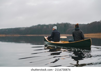 Two people in a green canoe along the calm lake in late autumn or early spring. Paddling lifestyle, enjoying tranquil and calm water and beautiful scenery - Powered by Shutterstock