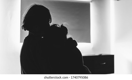 Two people hugging each other before a coffin in a lonely, sad room. They might be in a funeral, burial, hospital, church or waiting for cremation. Black and white mourning, grief, sorrow and death. - Powered by Shutterstock