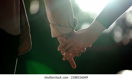 Two people joining hands outside with sun flare in background. Closeup girlfriends joined hands together
