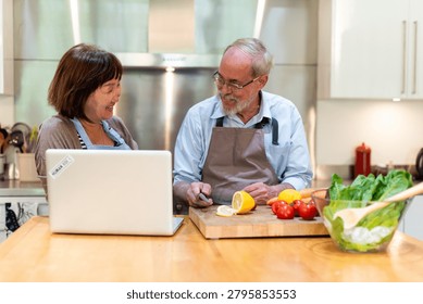 Two people in a kitchen, smiling and preparing food together. A laptop is open on the counter, surrounded by fresh vegetables and fruits.