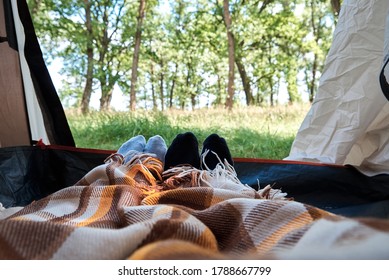Two people lie in a tourist tent, inside view. Feet under the covers in the tent. Tourist camp