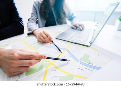 Two People Looking At City Map With Laptop At Table