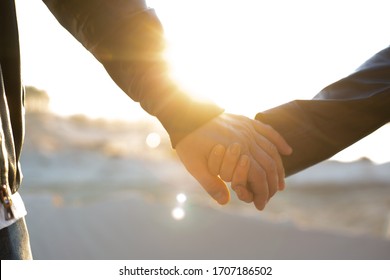 Two people male and female palms in black leather jacket and against backdrop of glare from sun on street. Close up