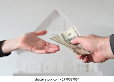 Two People (male And Female) Passing Money Against A White House. Mortgage, Housing Market, Home Loans And Property, Management Concept. No People. Copy Space