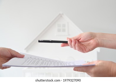 Two People (male And Female) Signing A Contract Against A White House. Mortgage, Housing Market, Home Loans And Property, Management Concept. No People. Copy Space