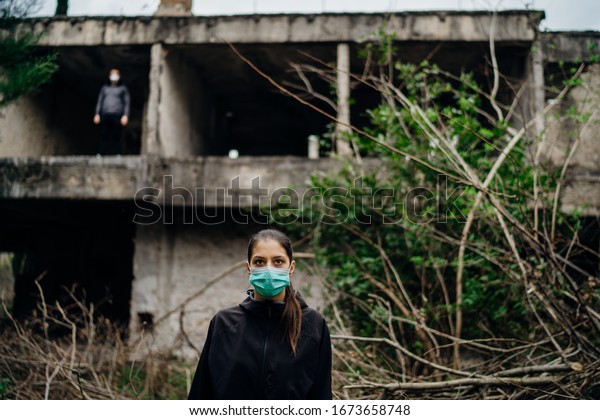 Two people in masks in a abandoned\
location.Abandoned city ruins. Divided by incurable infectious\
disease,catastrophe.Isolation.Loved one\
illness,distance.