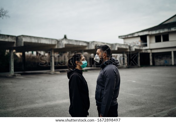 Two people in masks talking from\
distance.Couple being divided by incurable infectious\
disease.Infection control,isolation.Loved one illness.Saying\
goodbye.Farewell.Letting go.Toxic\
relationship.