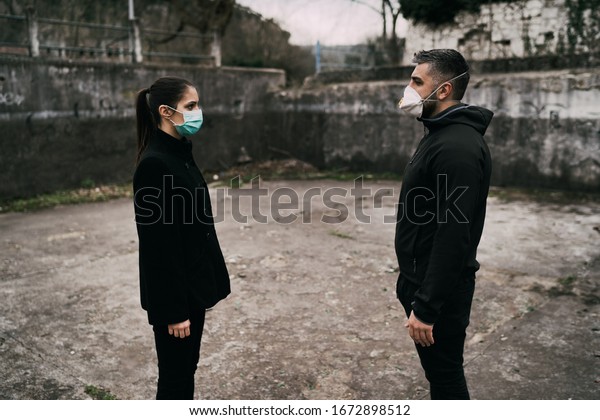 Two\
people in masks talking from distance.Couple being divided by\
incurable infectious disease.Infection control,isolation.Loved one\
illness.Saying goodbye.Farewell.Toxic\
relationship.